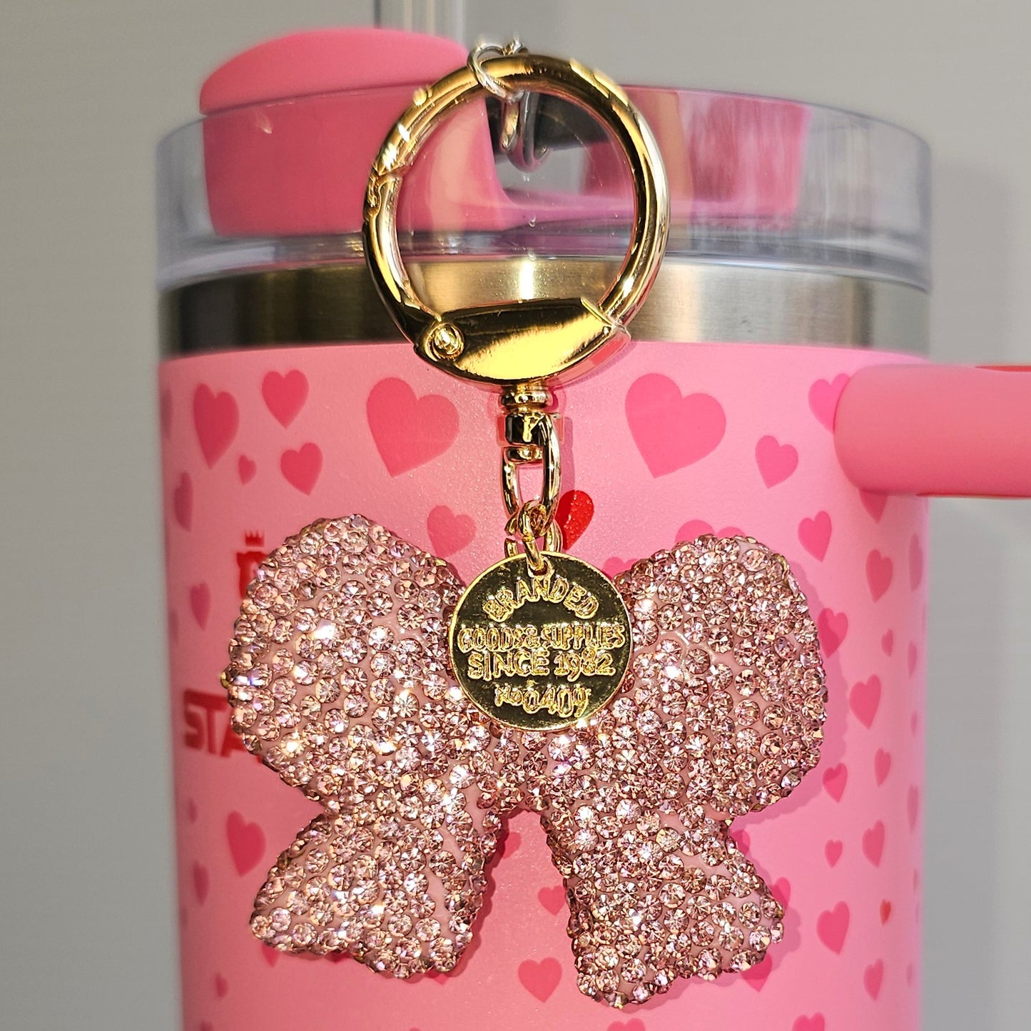 Pink and Gold Glitter Coquette Bow charm for tumbler straw, purse, bag, keychain, or backpack. Taken with flash.