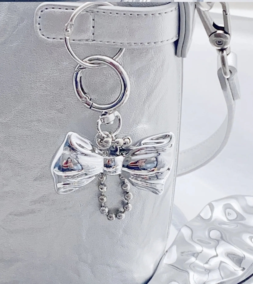 Silver bow charm accessorizing purse