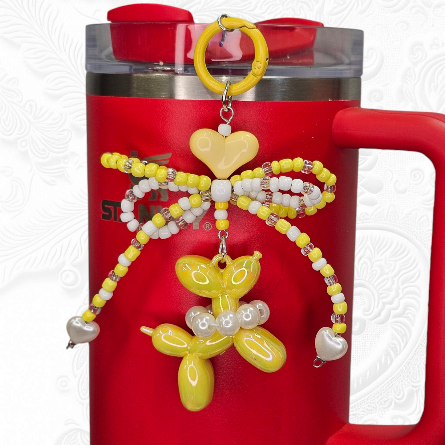 Yellow and white beaded ribbon bow, yellow heart, and pearlescent yellow balloon dog charm pendant.