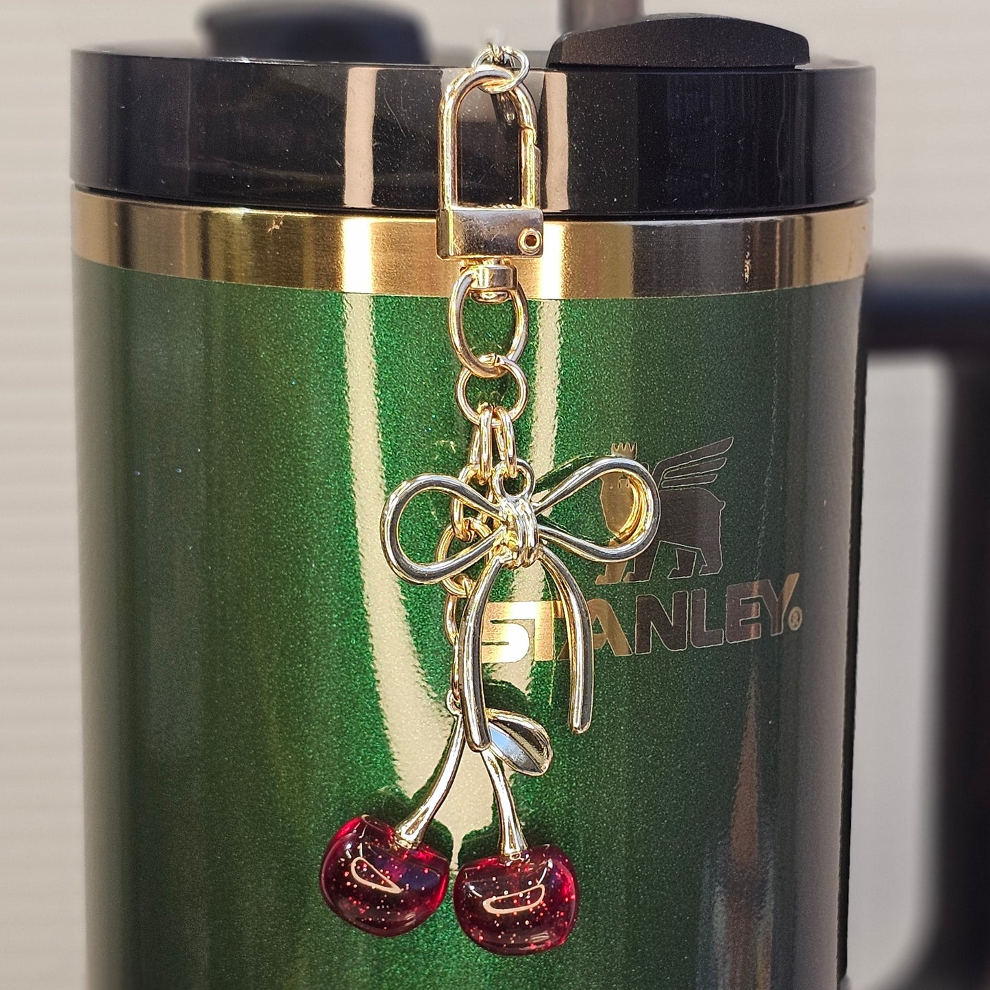 Red Glitter Cherries with a gold coquette Ribbon Bow Charm Pendant used as a tumbler straw charm. 