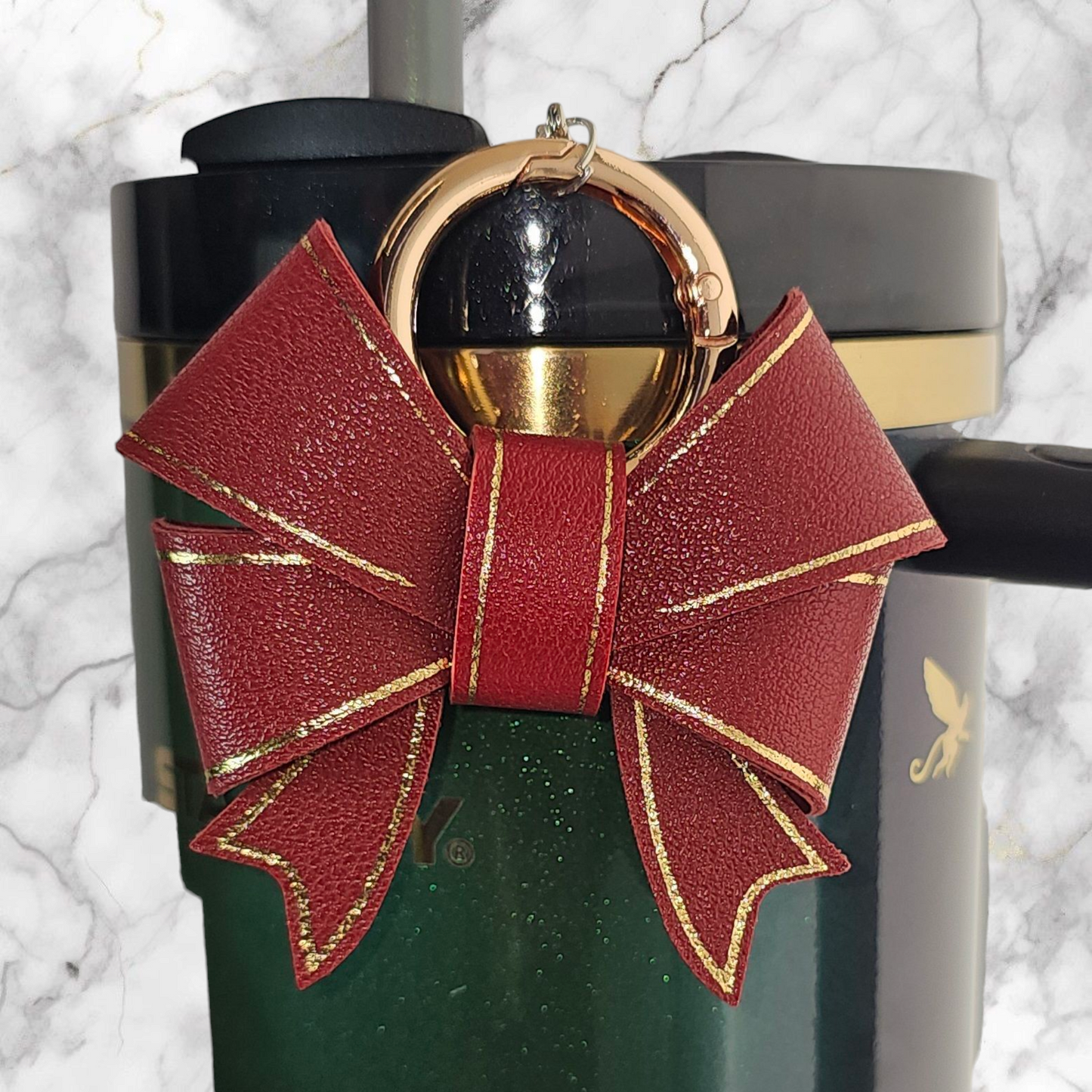 A luxury deep red faux leather bow trimmed in gold charm pendant that can be used as a charm for your tumbler, tumbler straw, purse, bag, keychain, backpack, or cellphone. 