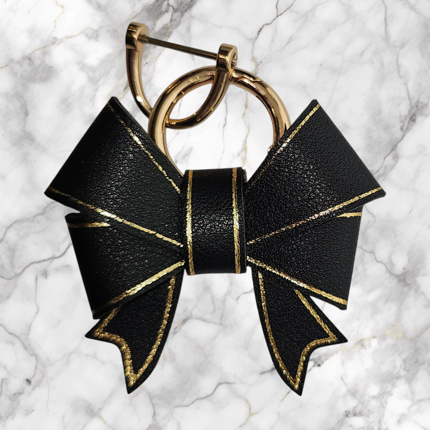A luxury black faux leather bow trimmed in gold charm pendant that can be used as a charm for your tumbler, tumbler straw, purse, bag, keychain, backpack, or cellphone. Pictured with extra gold keyring. 