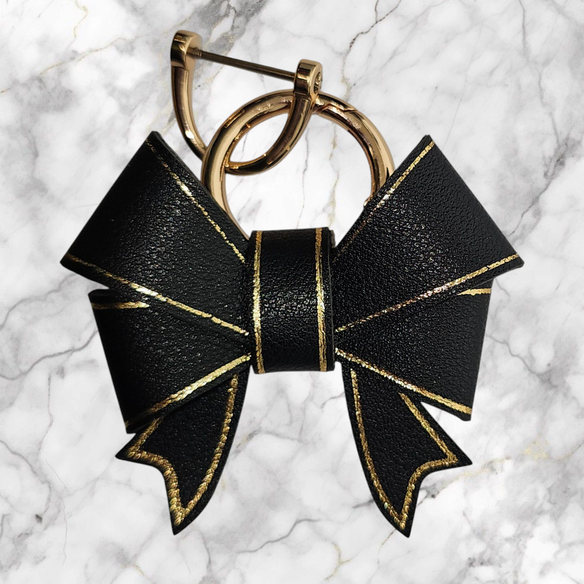 A luxury black faux leather bow trimmed in gold charm pendant that can be used as a charm for your tumbler, tumbler straw, purse, bag, keychain, backpack, or cellphone. Pictured with extra gold keyring. 