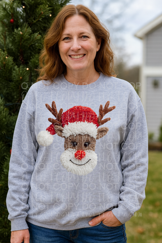 Reindeer faux yarn design on Christmas t-shirt and sweatshirt, featuring red hat and pom pom nose festive holiday graphic.