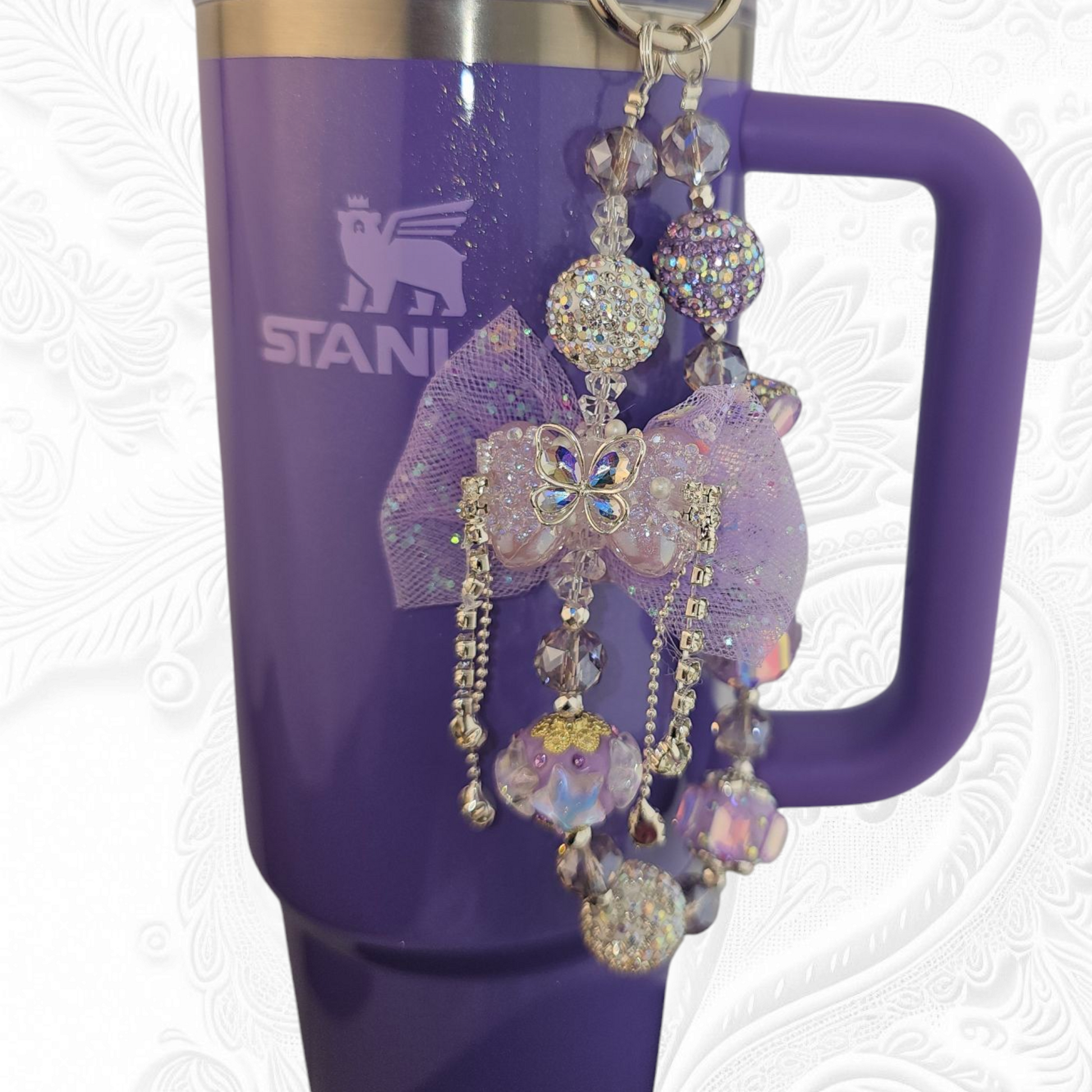 Deluxe Princess Beaded Tumbler Charm Necklace - Lavender Purple 
Iridescent Pearlescent Lavendar Purple Crystal Beaded Tumbler Charm Necklace. 

The center piece of this beautiful charm is the Jumbo Purple bow tie that is double-sided. One side has a purple sequin star while the other side has a crystal butterfly and diamonds. (diamonds are not real)