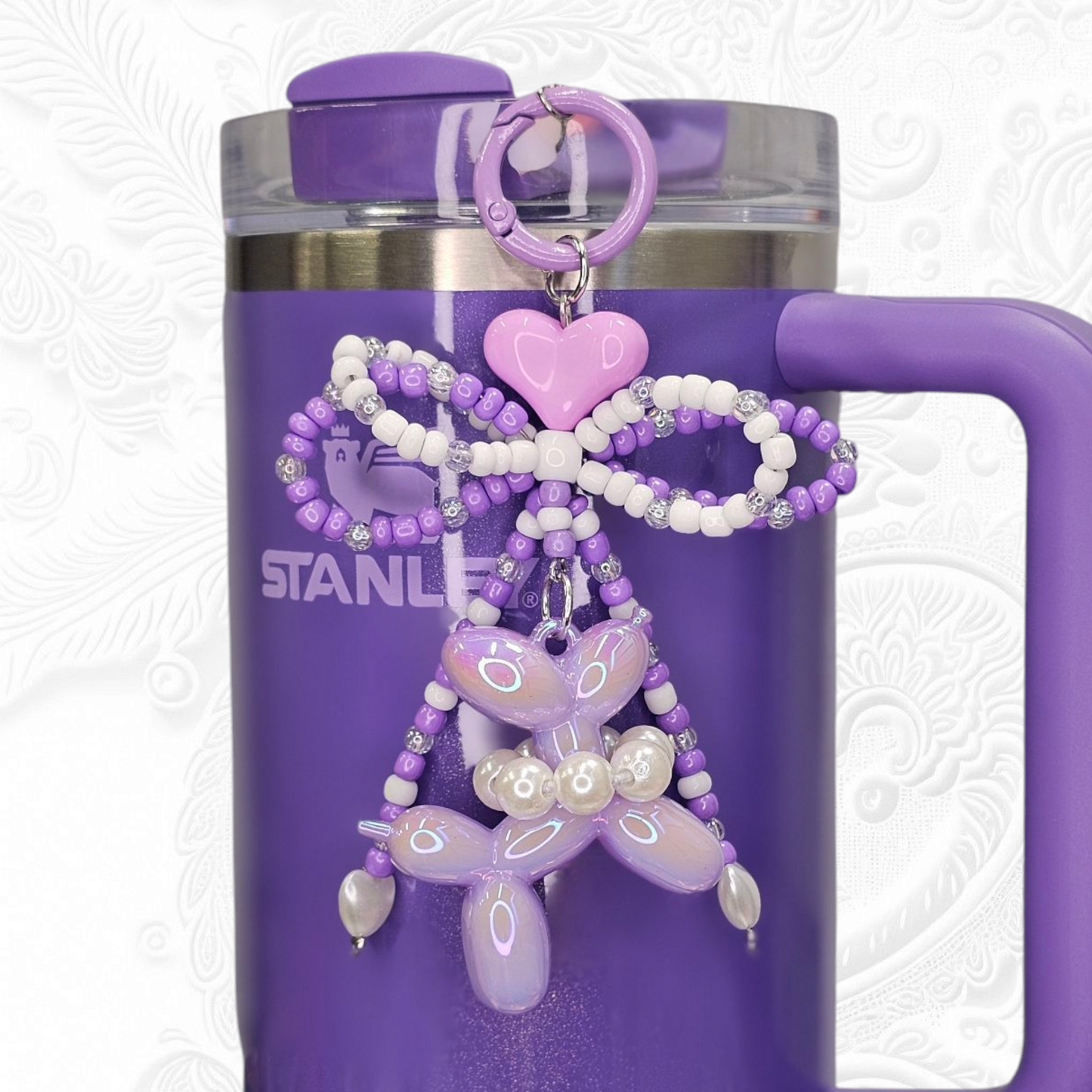 Purple and white beaded ribbon bow, purlple heart, and pearlescent purple balloon dog charm pendant. 