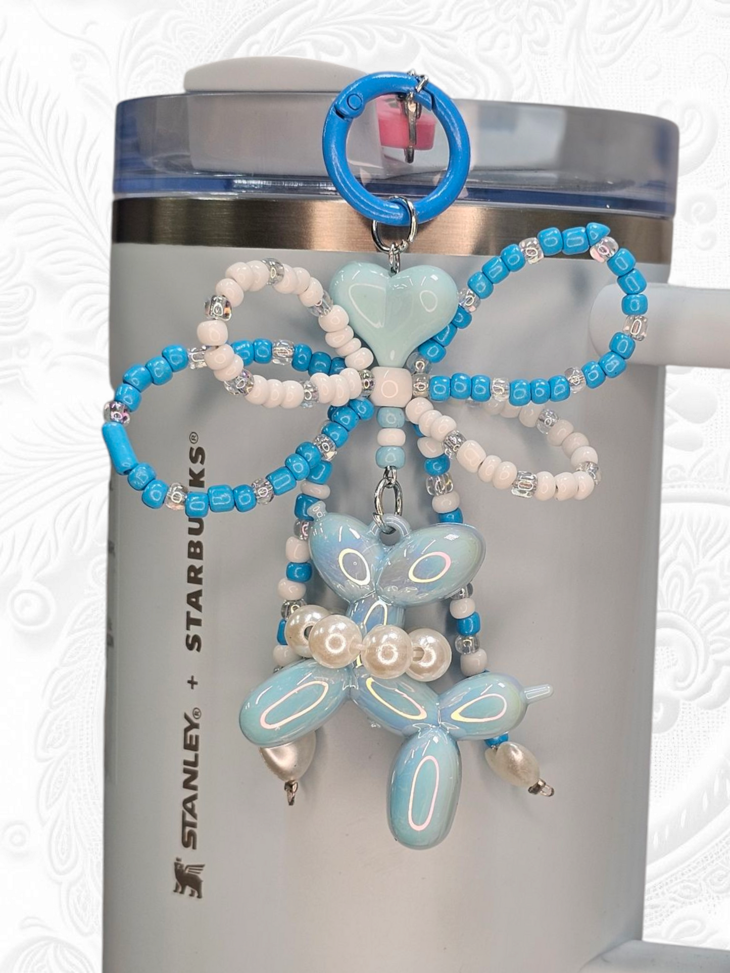 Blue and white beaded ribbon bow, blue heart, and pearlescent blue balloon dog charm pendant. 