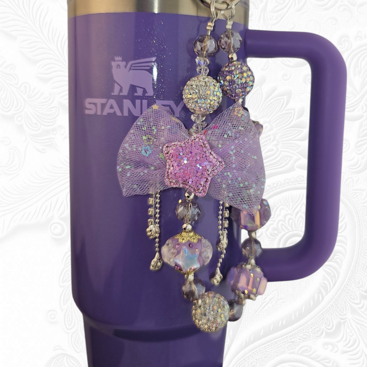 Deluxe Princess Beaded Tumbler Charm Necklace - Lavender Purple 
Iridescent Pearlescent Lavendar Purple Crystal Beaded Tumbler Charm Necklace. 

The center piece of this beautiful charm is the Jumbo Purple bow tie that is double-sided. One side has a purple sequin star while the other side has a crystal butterfly and diamonds. (diamonds are not real)