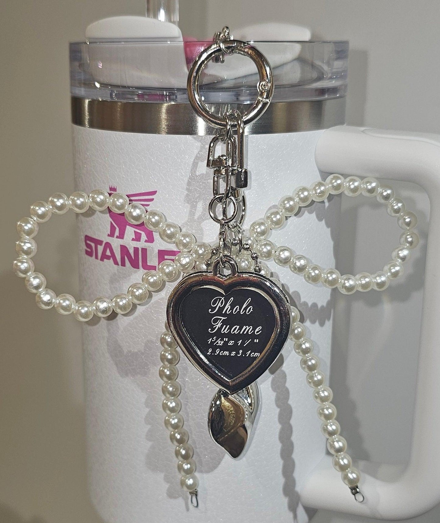 Croquet White Faux Pearl Ribbon Bow, Picture Locket, and Silver Heart Charm For Stanley, Brumate, Simple Modern, Yeti, Starbucks, any Tumbler, Straw, Cup Handle, Mini Stanley, Keychain, Purse, or Backpack. 
☆☆☆ Very Versatile ☆☆☆
☆ Clips easily to straw charm adaptor. 
☆ Heart shaped picture locket is double-sided. 
☆ Pieces can be seperated and used individually. 
☆ Cup, Straw, and Straw Charm Adaptor NOT included. 
☆ Colors may vary due to lighting and screen resolution.
