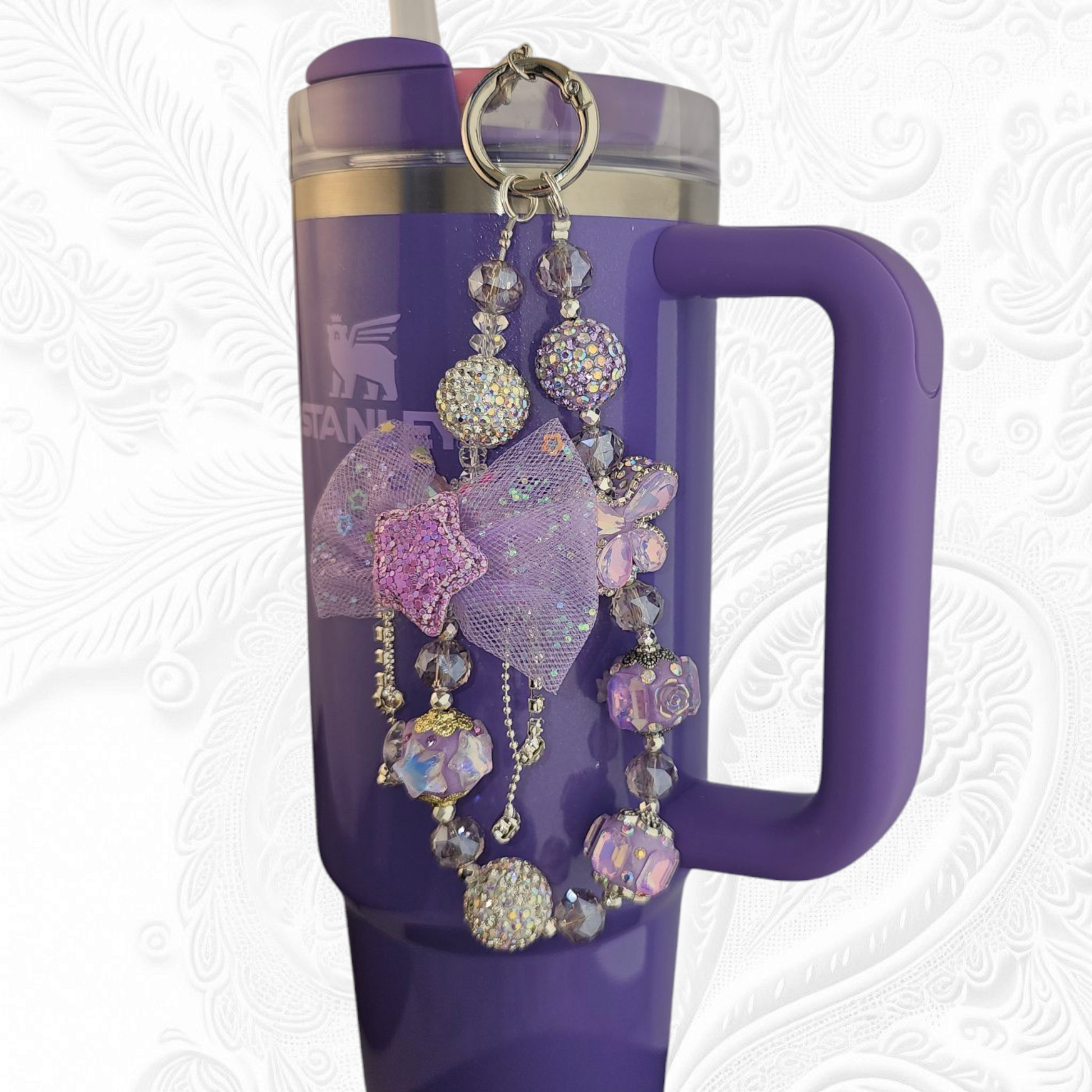 Deluxe Princess Beaded Tumbler Charm Necklace - Lavender Purple 
Iridescent Pearlescent Lavendar Purple Crystal Beaded Tumbler Charm Necklace. 

The center piece of this beautiful charm is the Jumbo Purple bow tie that is double-sided. One side has a purple sequin star while the other side has a crystal butterfly and diamonds. (diamonds are not real)